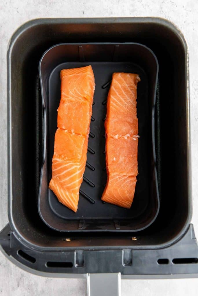 Two strips of salmon in the air fryer pan.