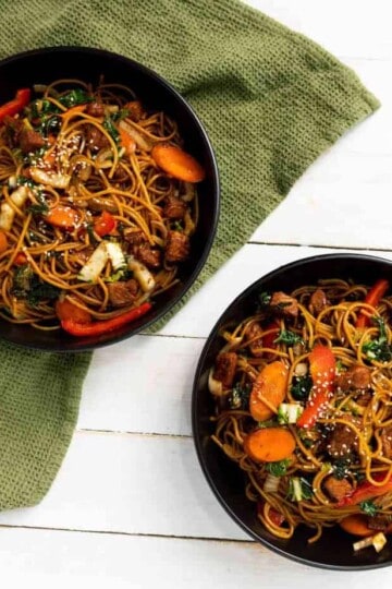 Two bowls of instant pork lo mein on a green cloth in the background.