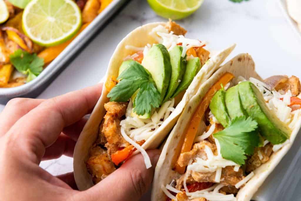 A person holding the sheet pan chicken fajitas.