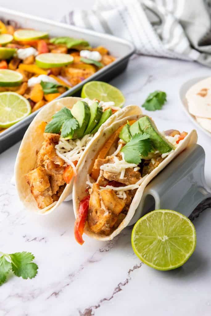 Two sheet pan chicken fajitas with lemon on the side.