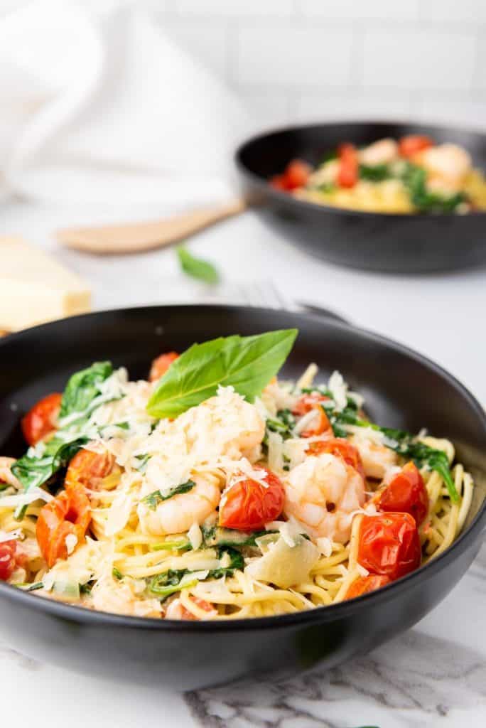 Close up photo of spaghetti scampi e Spinaci with spatula and cheese on the background.