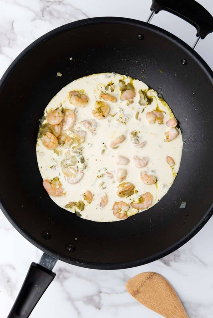 Peeled shrimp simmered with cream in a pan.