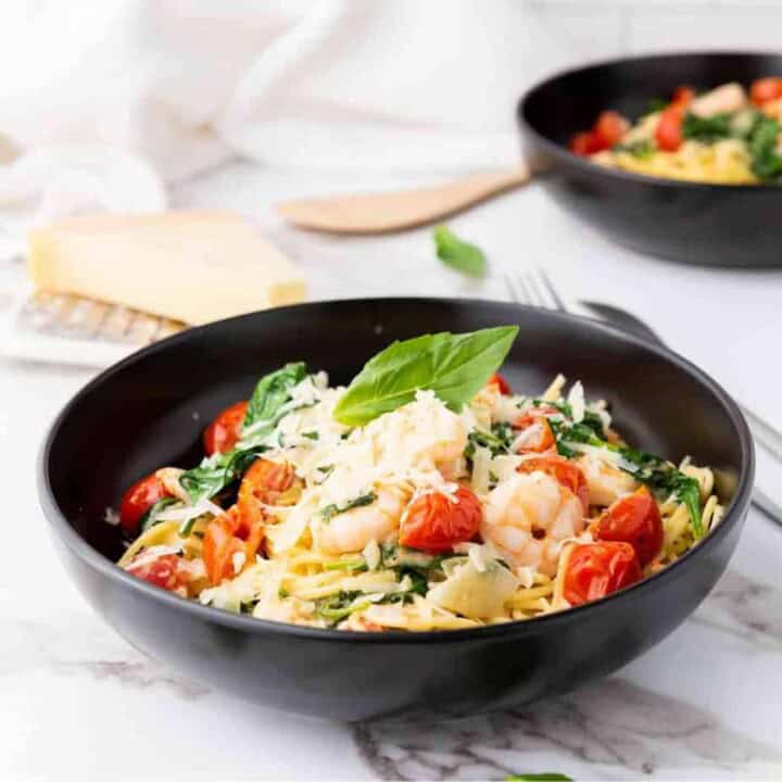 Close up photo of spaghetti scampi e Spinaci with spatula and cheese on the background.