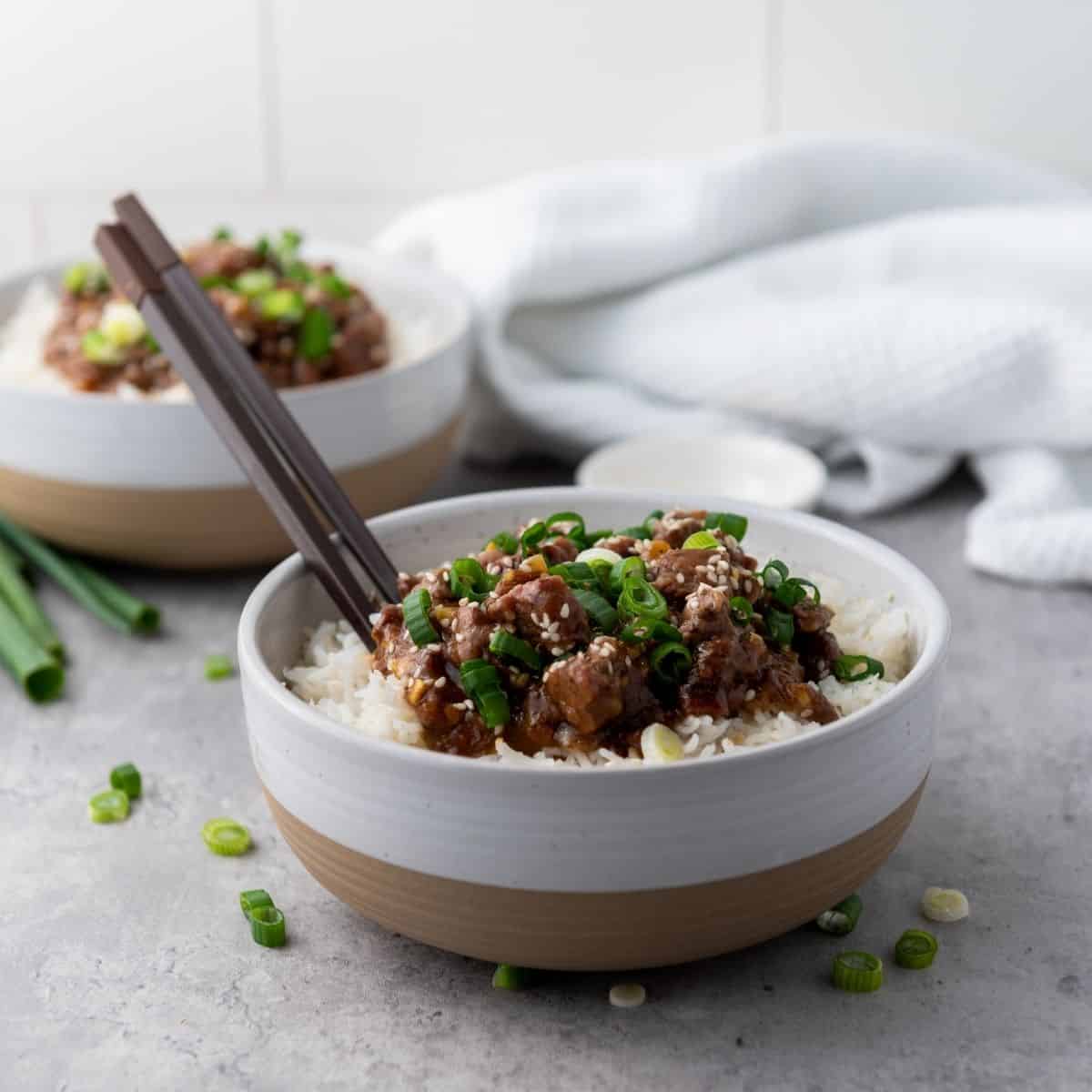 Slow cooker Mongolian Beef in a bowl with chopstick.