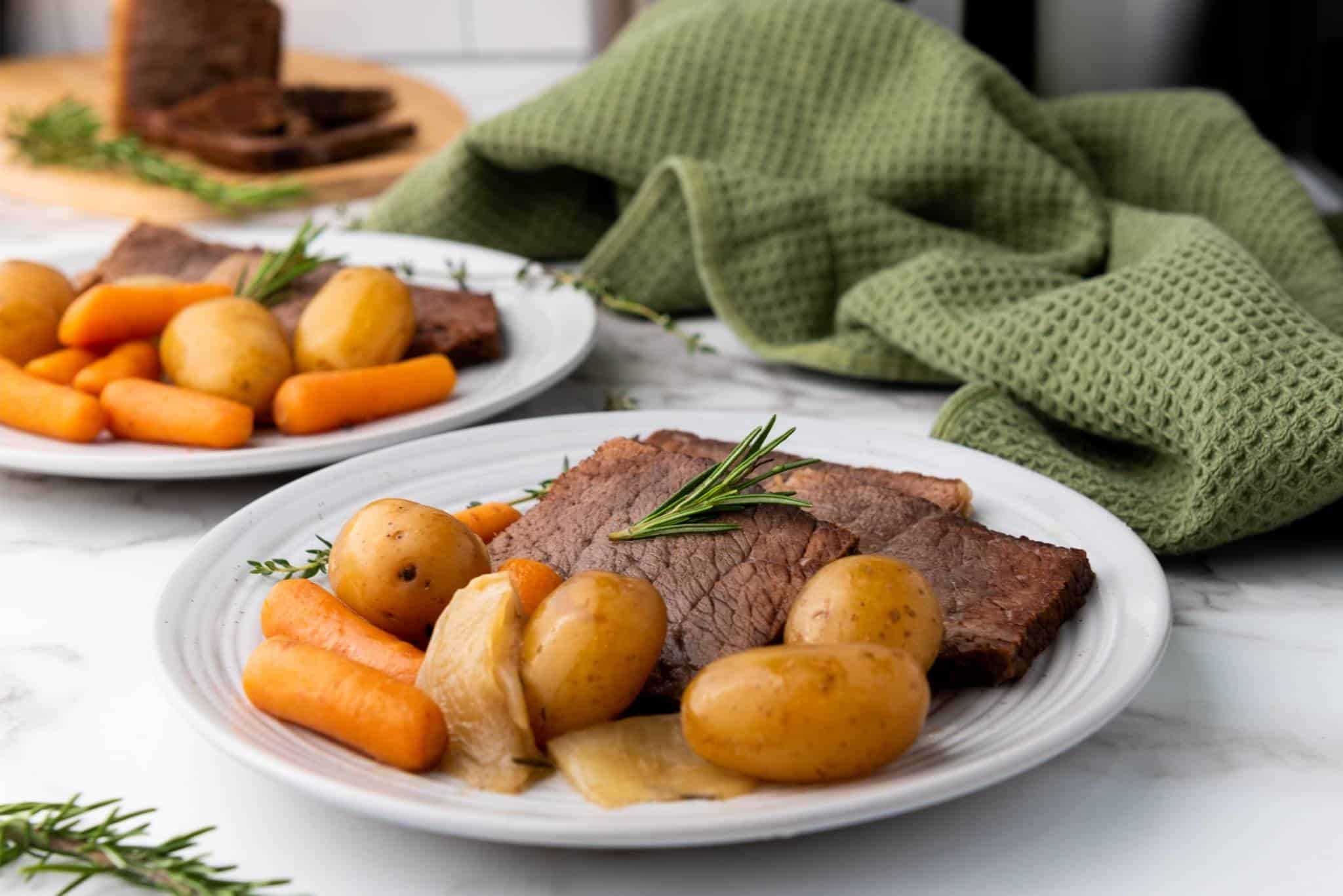 Served rump roast in a plate with vegetables on the side.