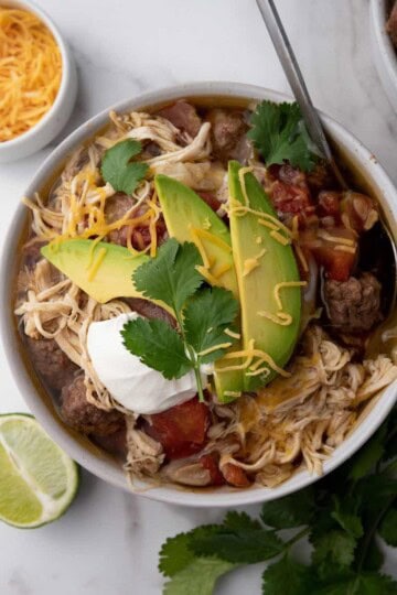 A photo of crockpot slow cooker taco soup with leaves and lemon on the side.