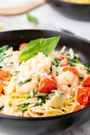 Close up photo of spaghetti scampi e Spinaci with spatula and cheese on the background.