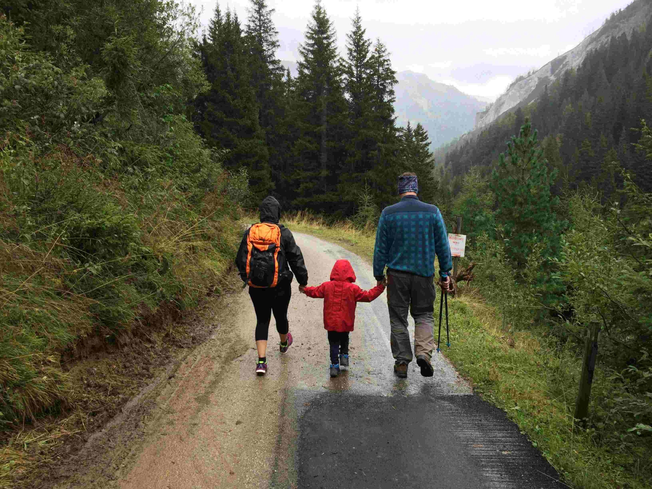 A family hiking in rainy weather on the road.