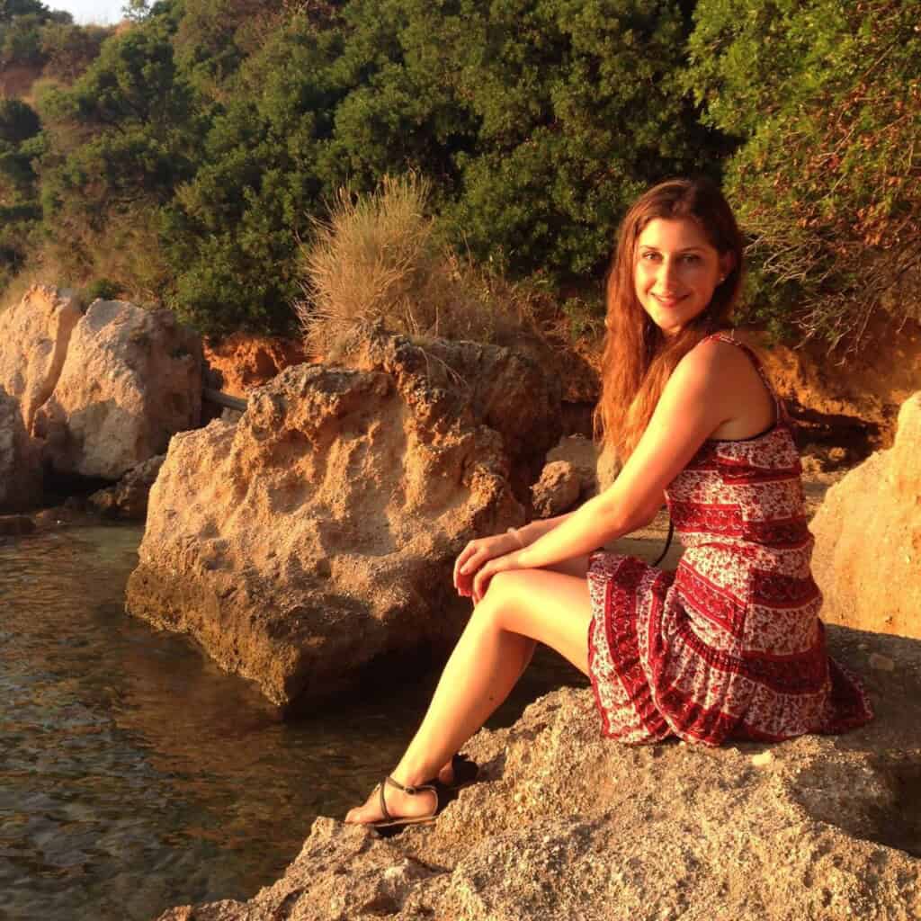 A girl sitting on the rocks besides the sea.