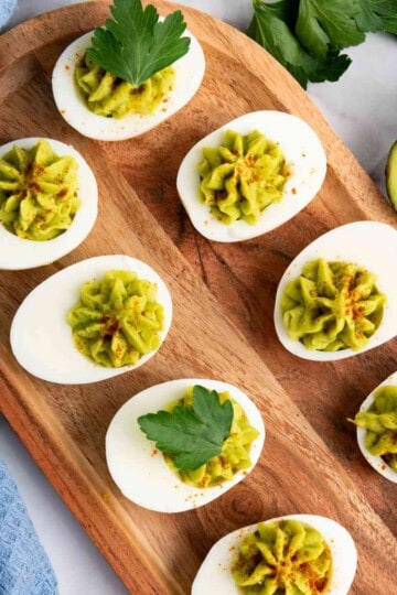 Served avocado Deviled eggs in a wooden board.