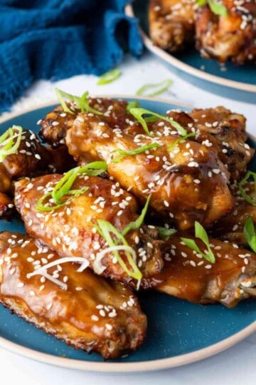 Served baked Asian sticky wings in a blue plate.