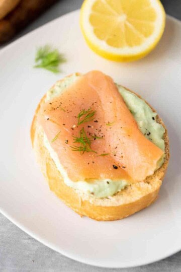 Smoked Salmon and Avocado Bruschetta served with a lemon wedge.