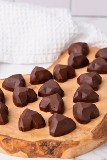 Heart shaped chocolate Nutella bonbons on a wooden board.