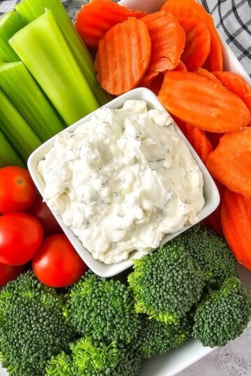 Fresh vegetables arranged around a bowl of creamy dip.