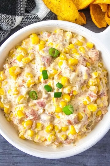 Creamy cold corn dip in a bowl, topped with green onions.