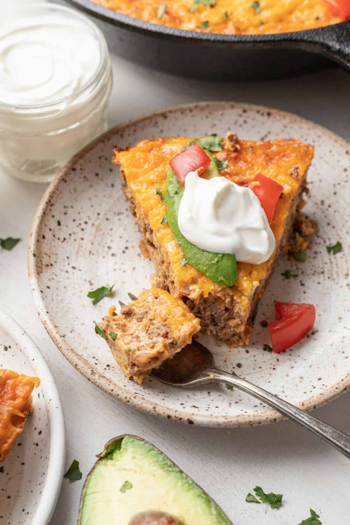 Sliced taco egg bake seved in a plate with fork nearby.