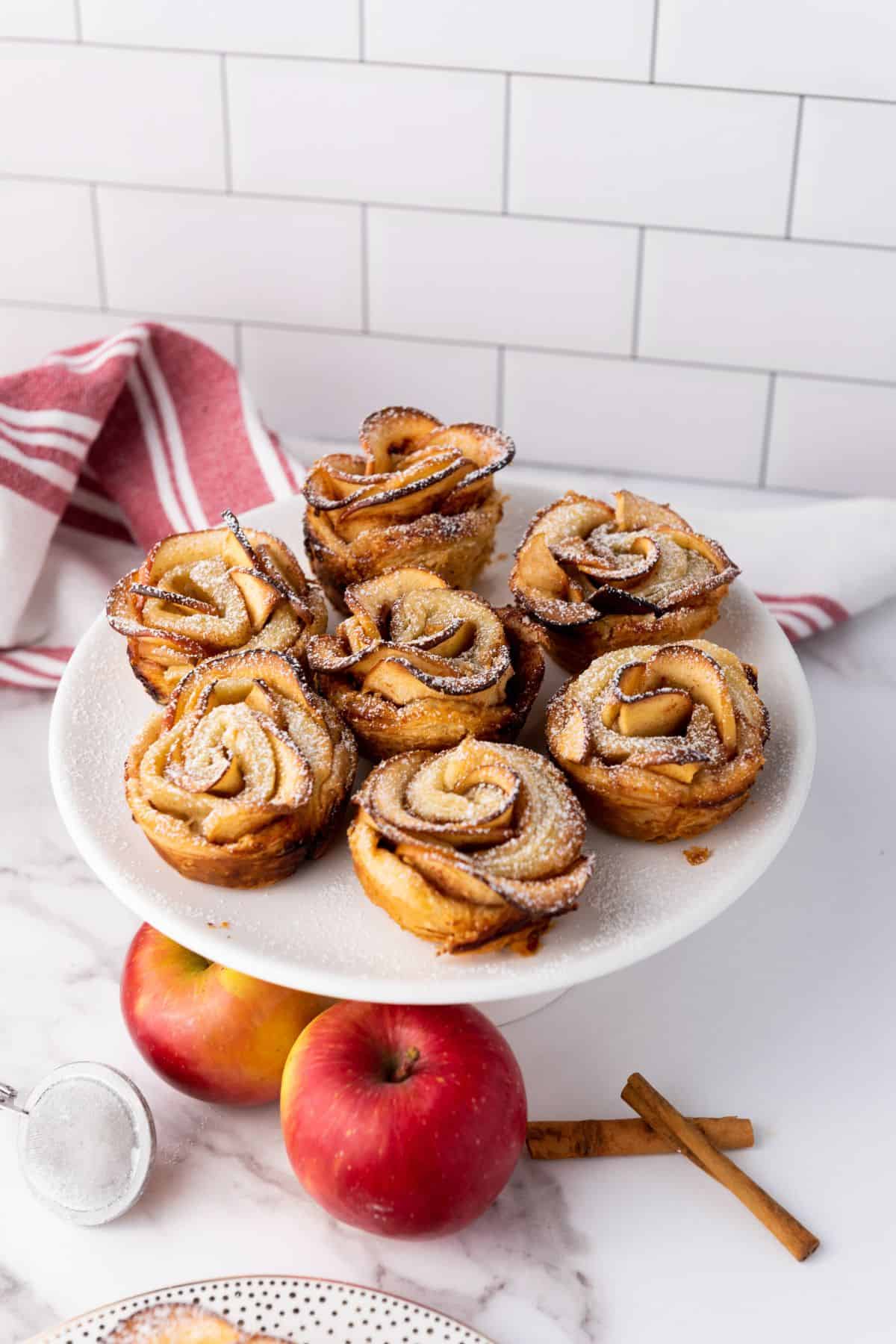 Served puff pastry apple roses with fresh apples nearby.