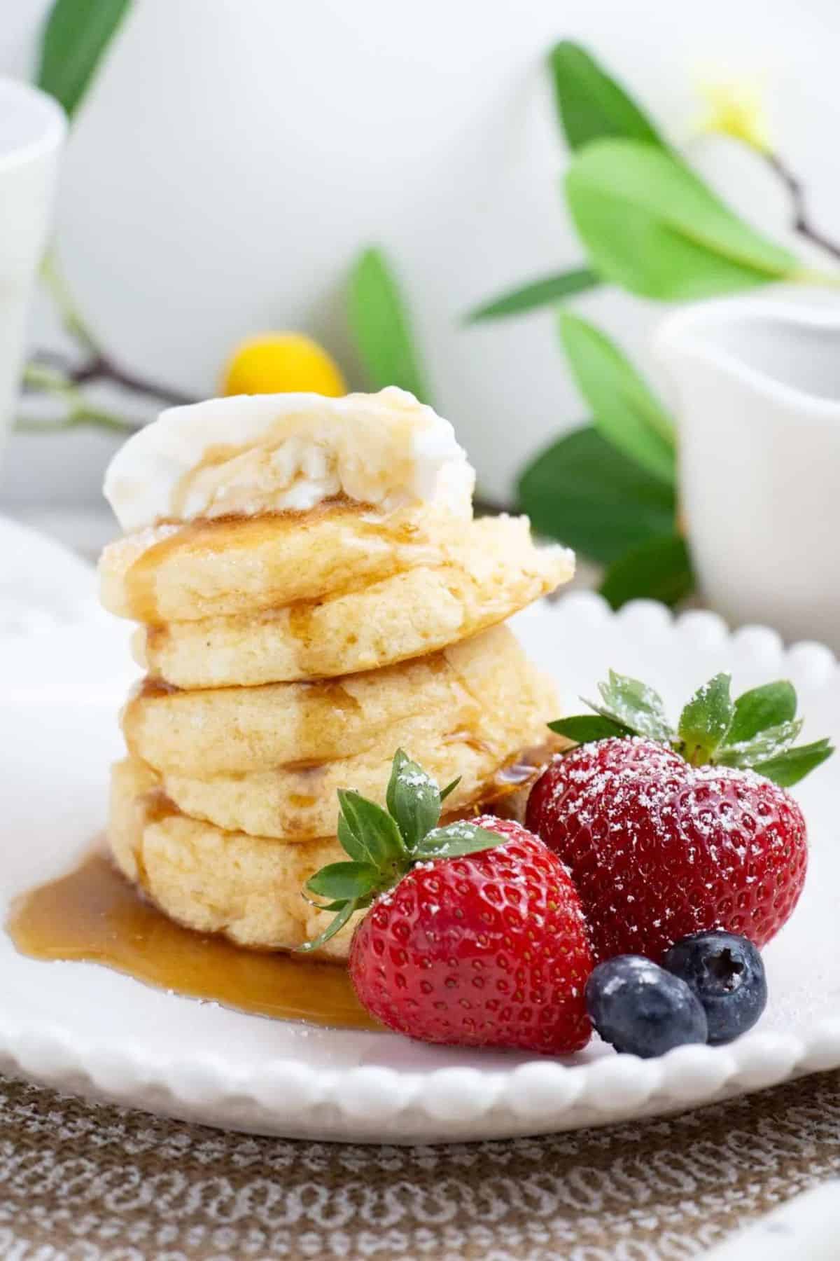 Layers of fluffy pancake with fresh berries on the side.