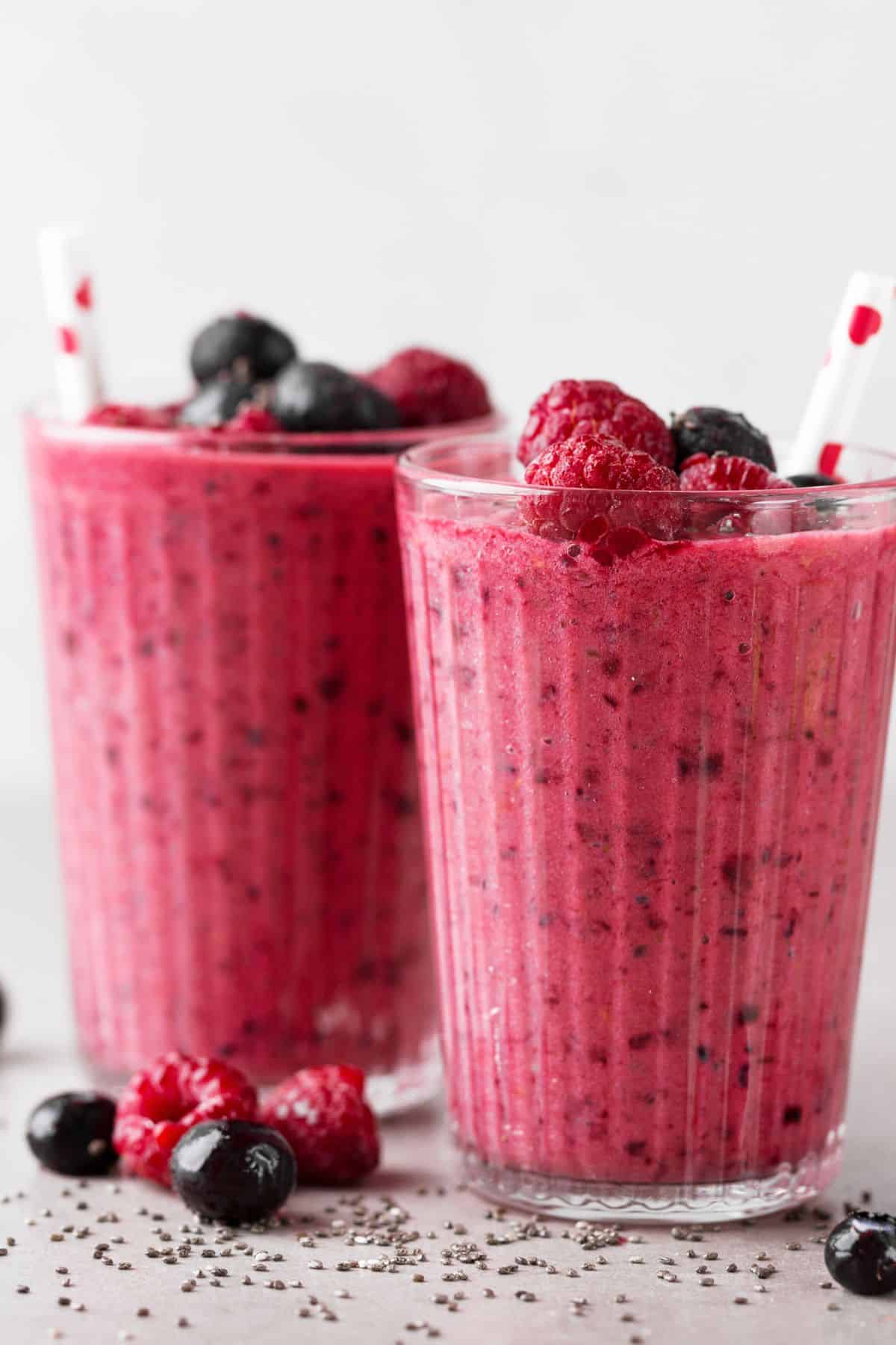 Two glass of smoothies topped with fresh berries.