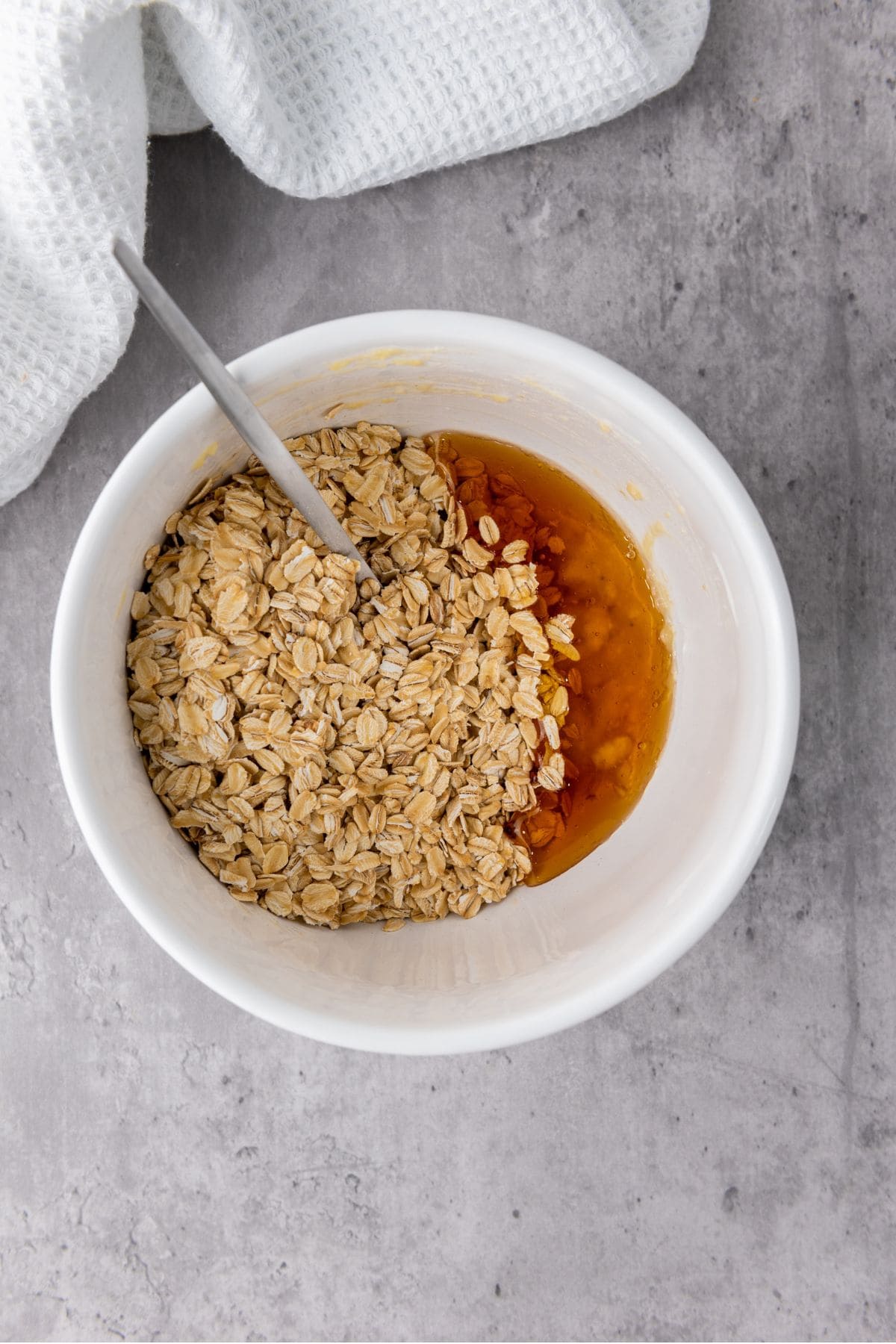 Bowl filled with rolled oats and drizzled with golden honey, ready to be mixed.