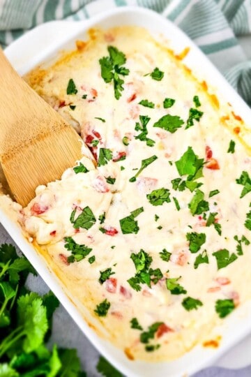 Simple queso dip in a baking dish, creamy and melted, with a spatula ready to serve it.