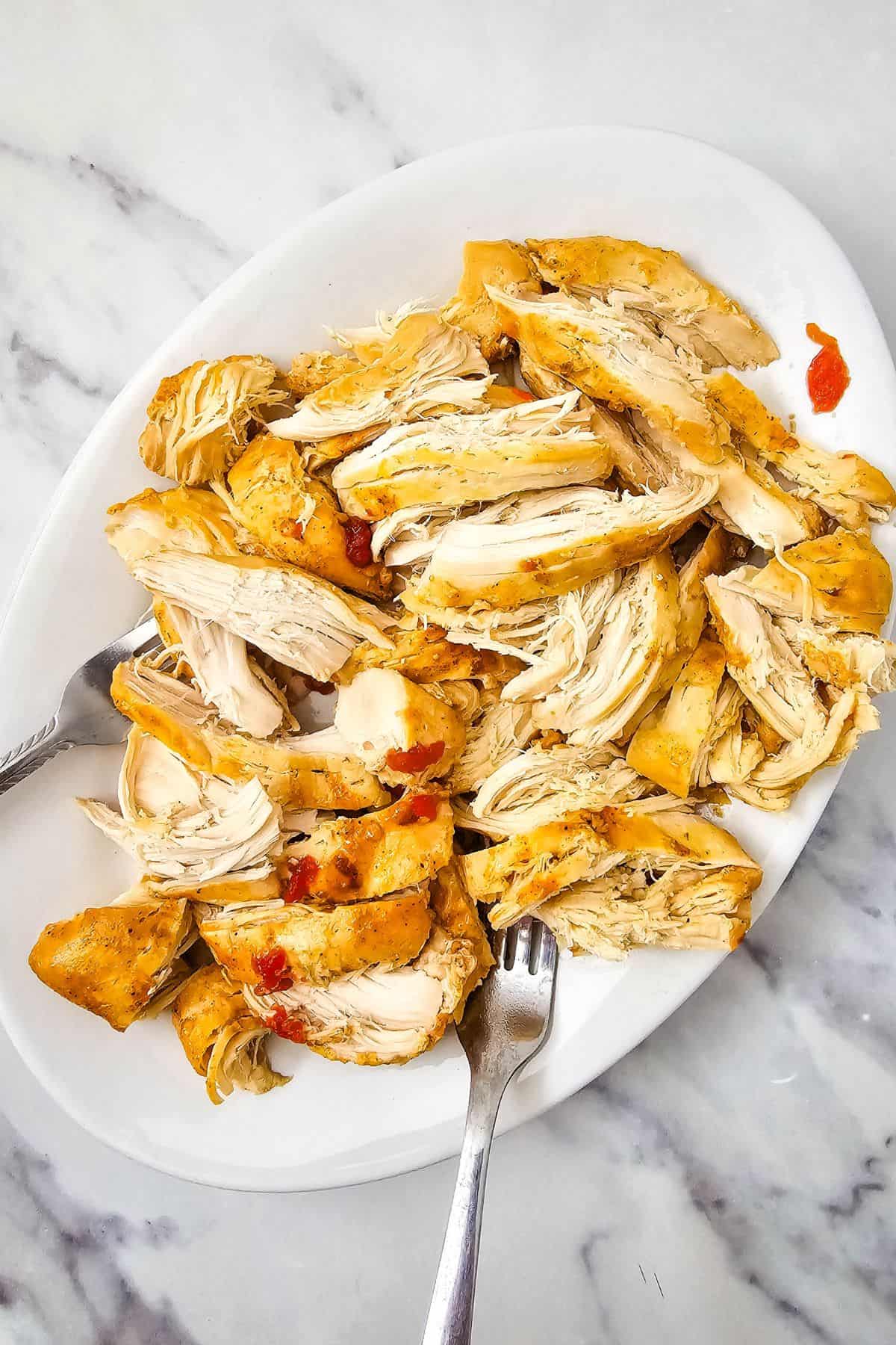 Shredded cooked chicken on a plate with a fork.