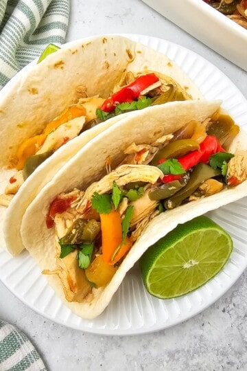 A plate of chicken fajitas with tender chicken, peppers, and onions served in warm tortillas.