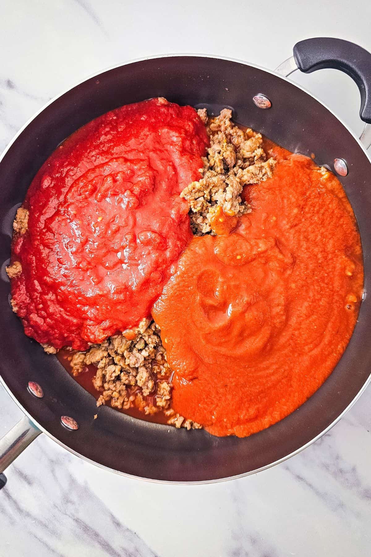 Ingredients being mixed in a pan with a spoon, creating a rich, saucy mixture.