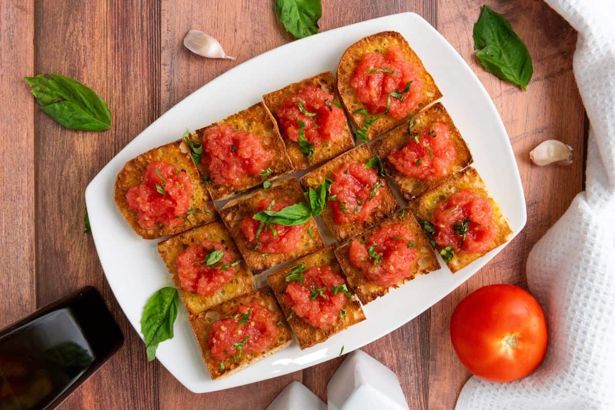 Pan con Tomate served on a plate, garnished with fresh basil and a drizzle of olive oil.
