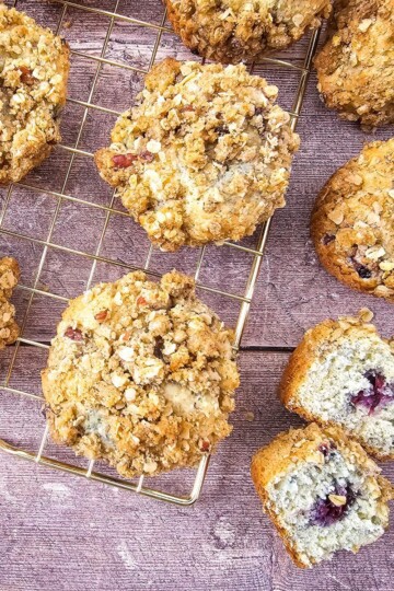 Muffins cooling on a wire rack, with one muffin broken open to display its moist interior.