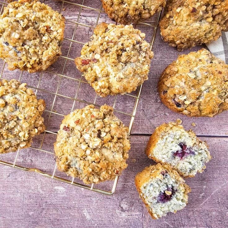 Muffins cooling on a wire rack, with one muffin broken open to display its moist interior.