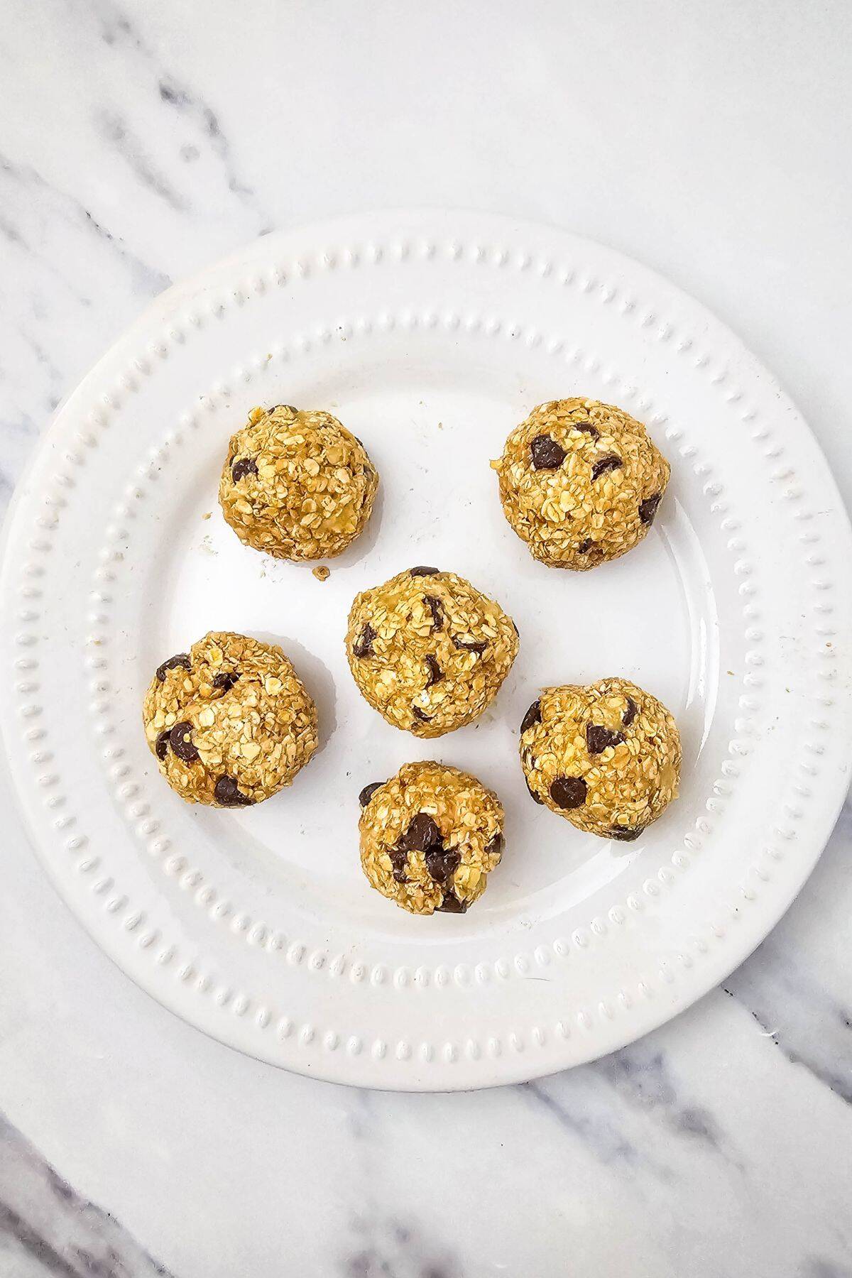 Shaped cookie dough balls arranged on a plate, ready to be baked.