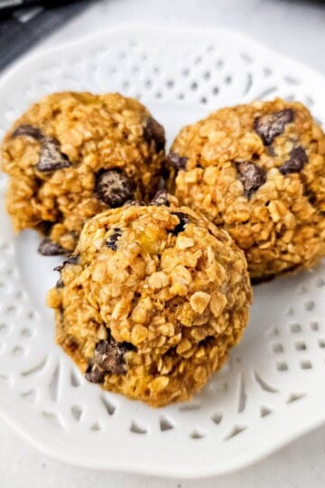 Three freshly baked banana oatmeal cookie balls on a plate.