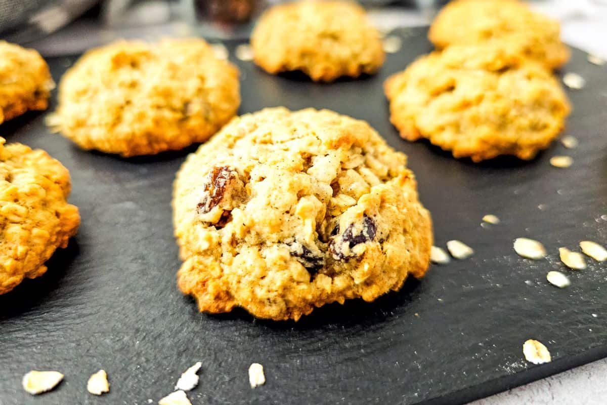 Freshly baked oatmeal raisin cookies with applesauce on a cooling rack.