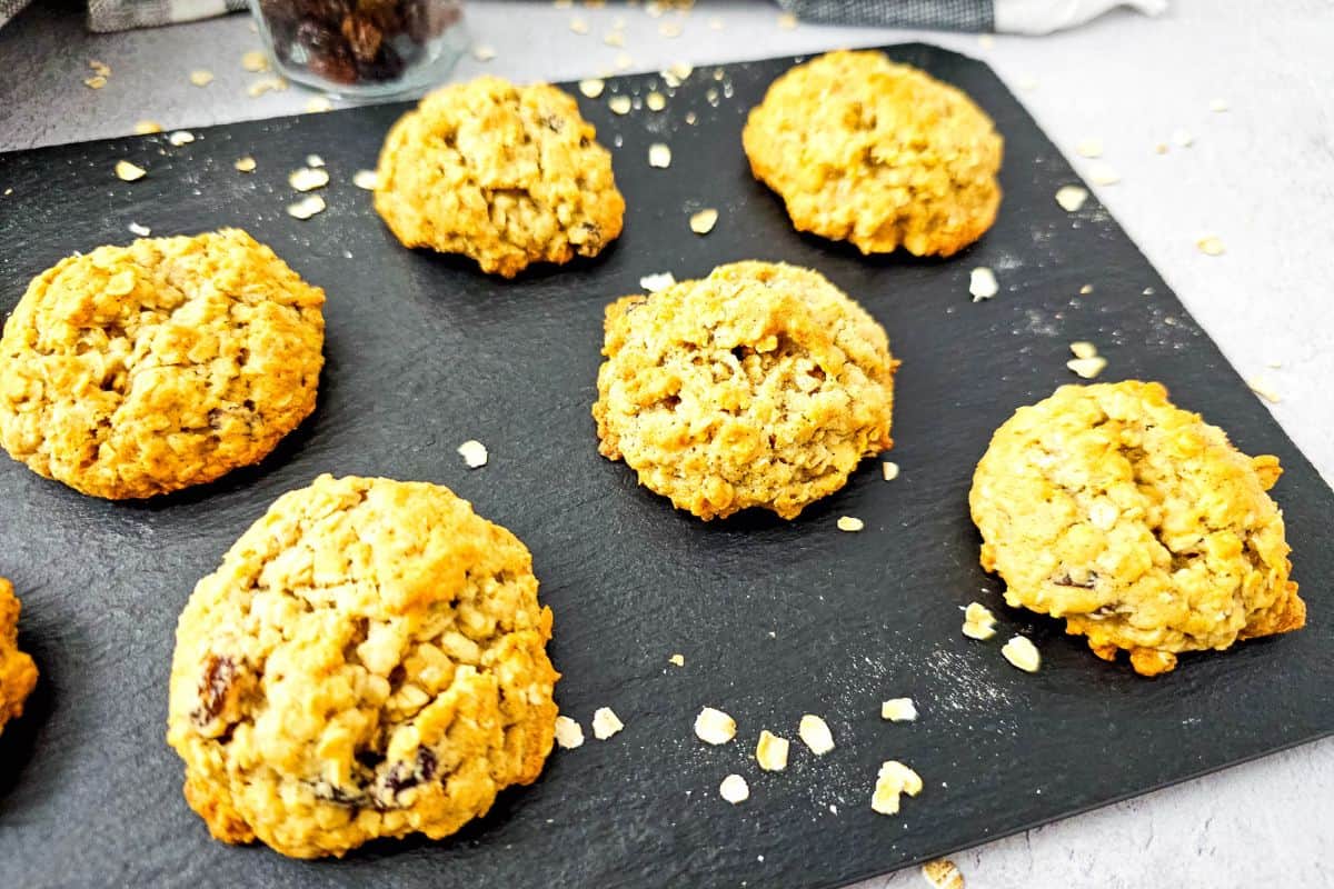 Freshly baked oatmeal raisin cookies with applesauce on a cooling rack.