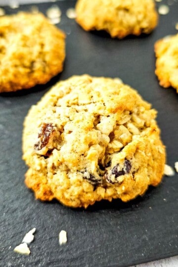 Freshly baked oatmeal raisin cookies with applesauce on a cooling rack.