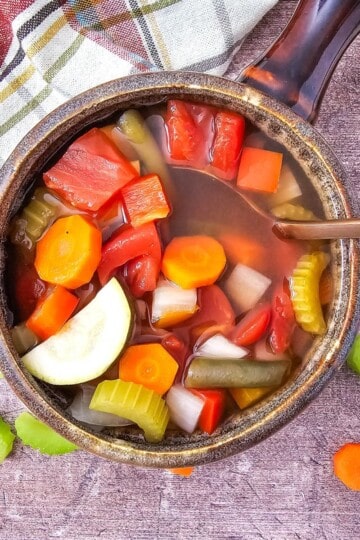 A bowl of vegetable soup served from the crockpot, with colorful vegetables.