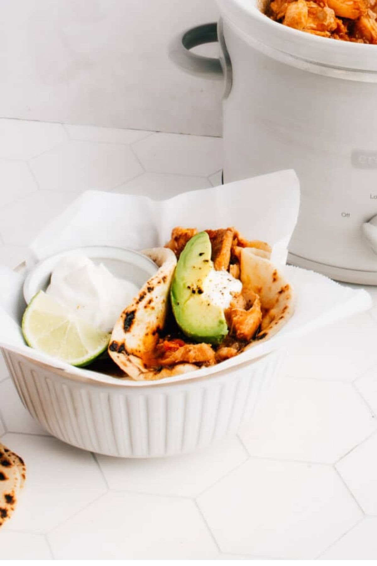 A bowl filled with chicken tacos, showing shredded chicken, salsa, and toppings in soft tortillas.