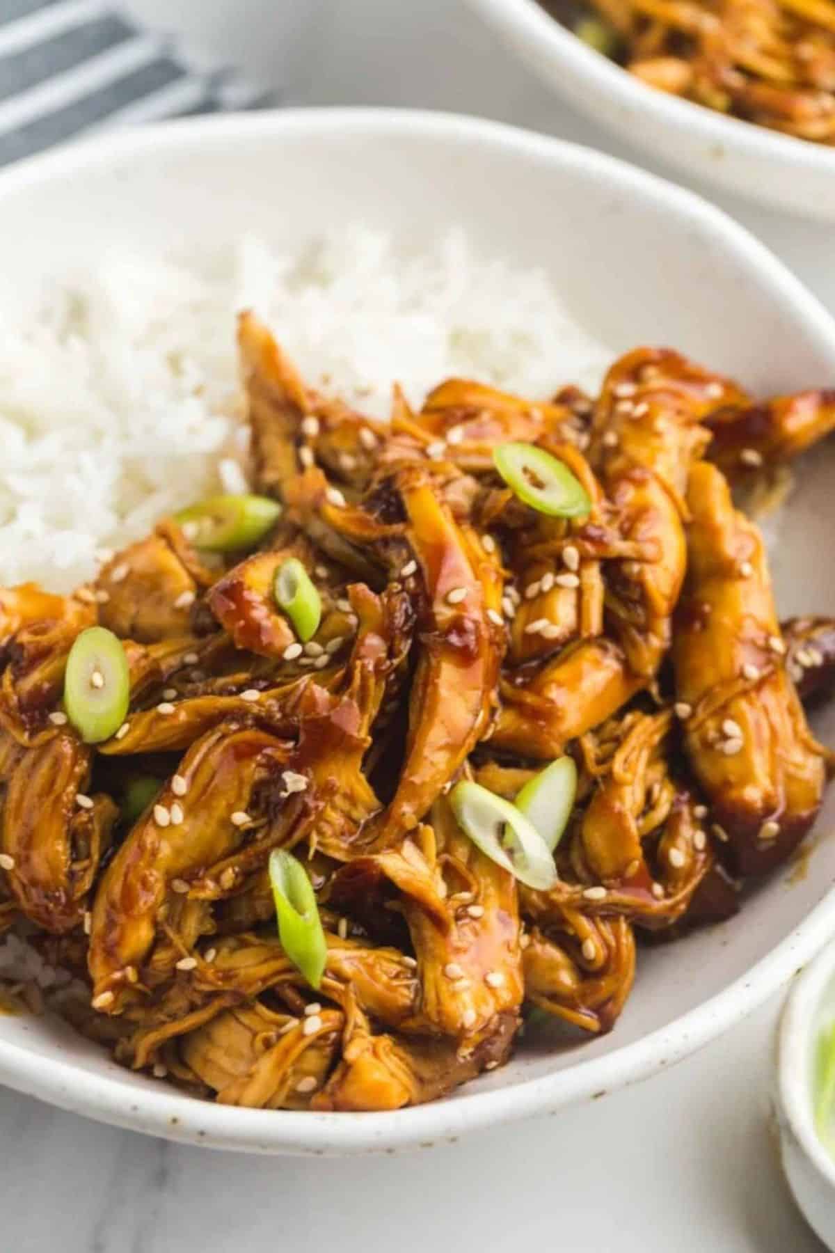 A bowl with chicken teriyaki strips served with rice.