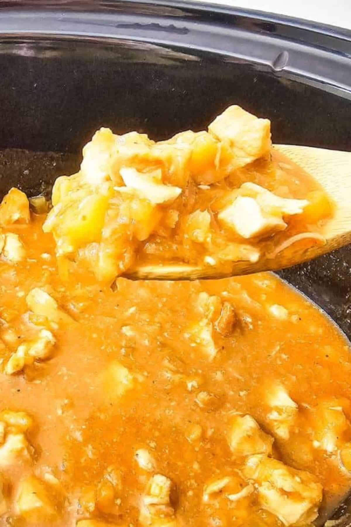 Close-up of sweet Hawaiian chicken on a spatula, with more chicken and sauce visible in the background.