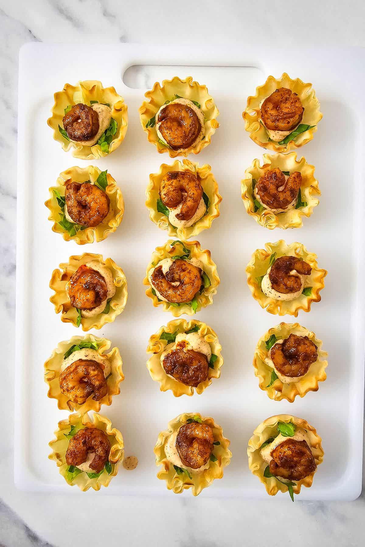 Shrimp placed on top of phyllo shells arranged on a serving dish.