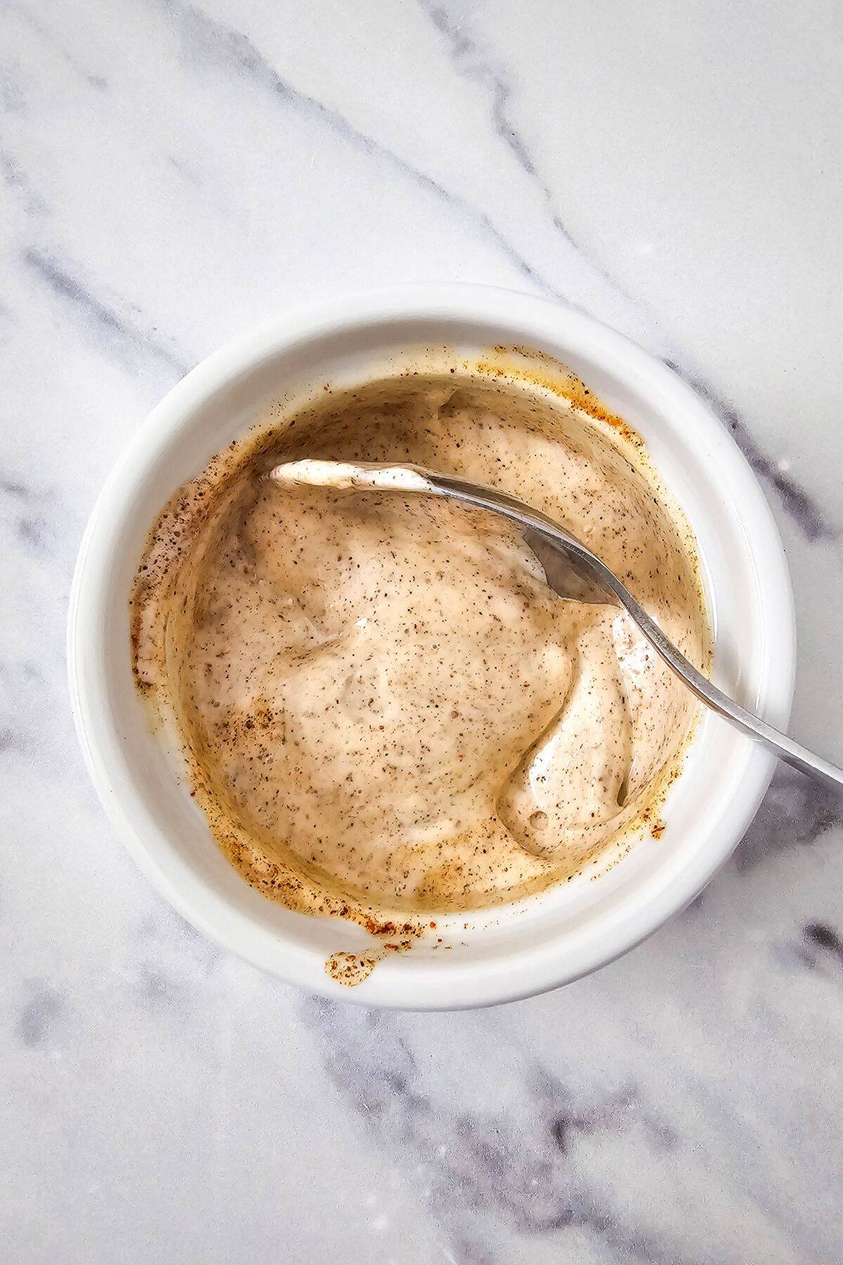 Small bowl with ingredients being mixed with a spoon inside.