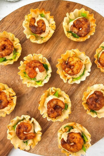 Chili Lime Shrimp Cups arranged on a wooden board with shrimp, sauce, and lettuce in phyllo shells.