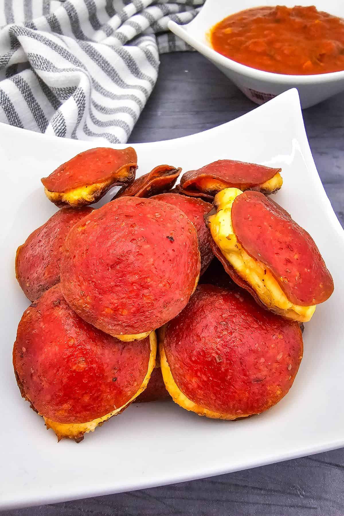 Close-up of a plate stacked with cream cheese-filled pepperoni rounds.