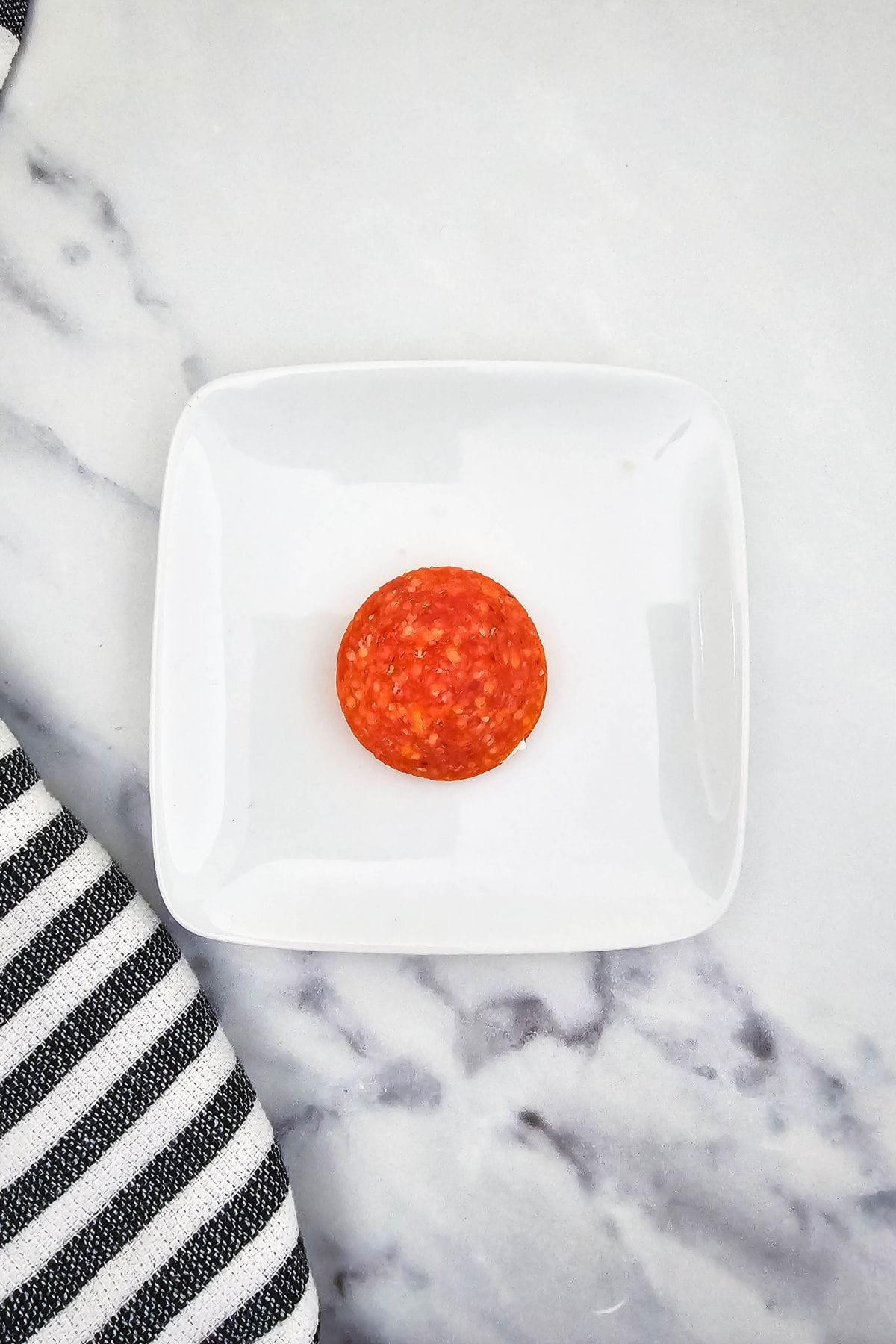 A single pepperoni in a plate.