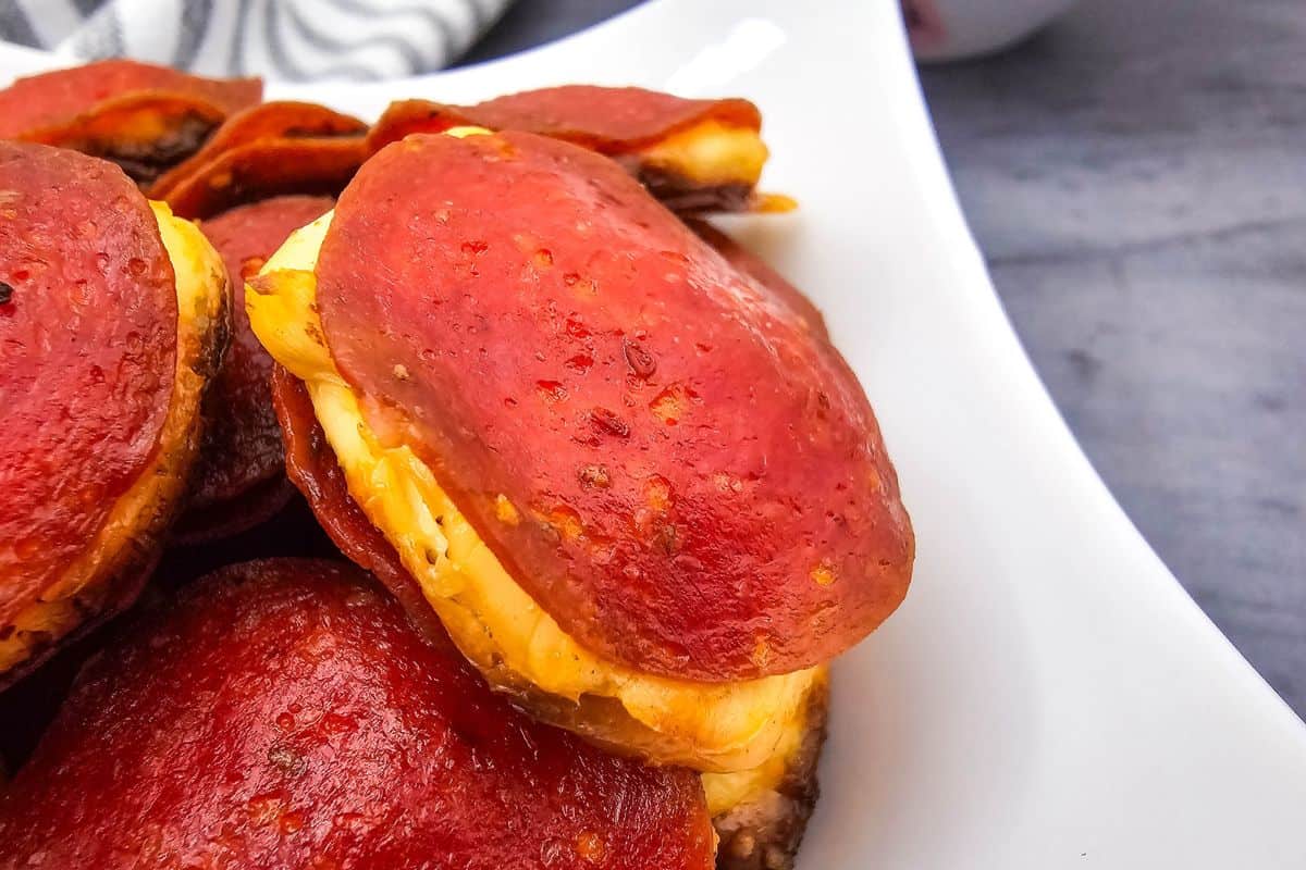 Close-up photo of a plate stacked with cream cheese-filled pepperoni rounds.