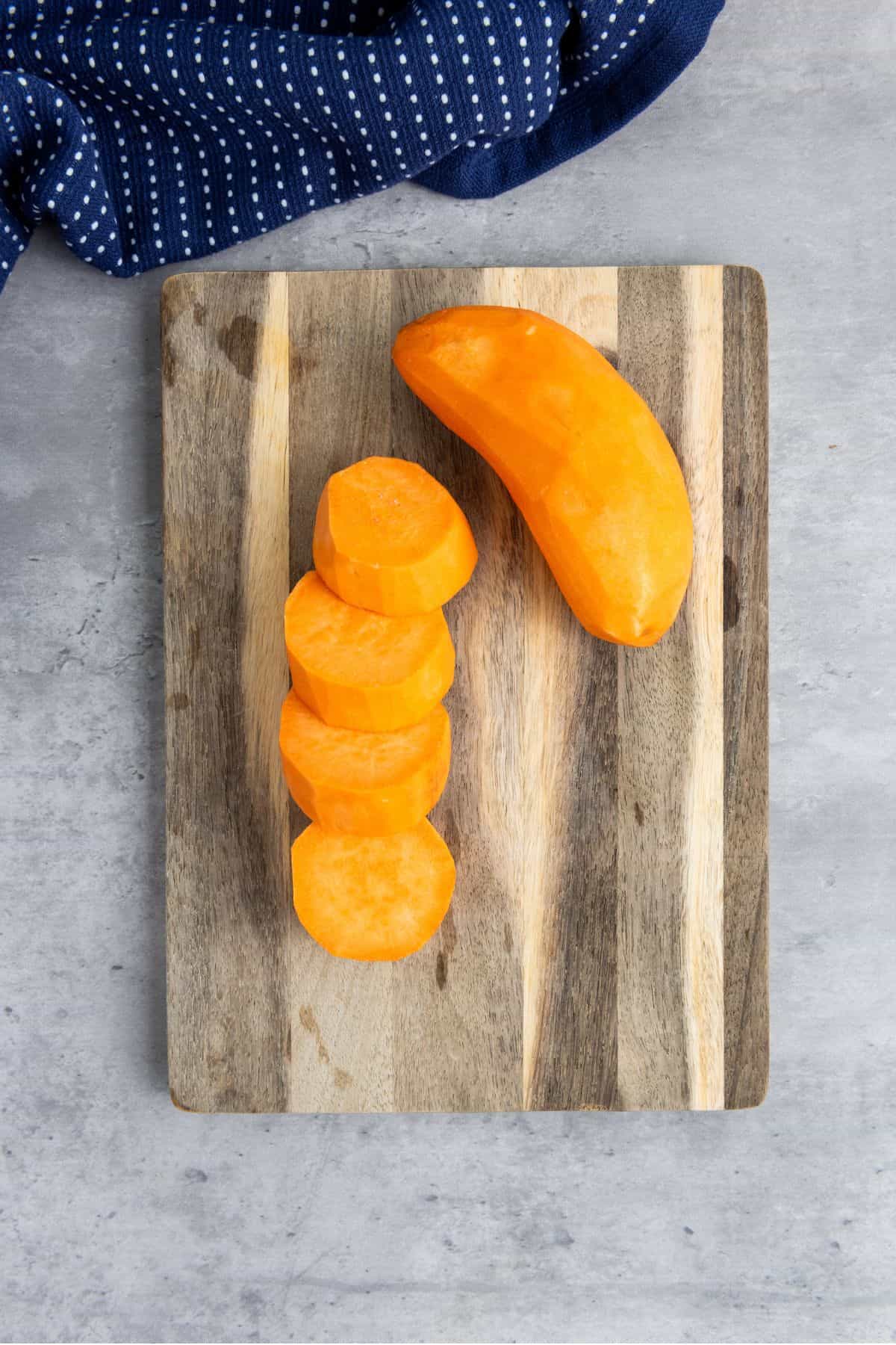 A chopping board with sliced sweet potatoes.