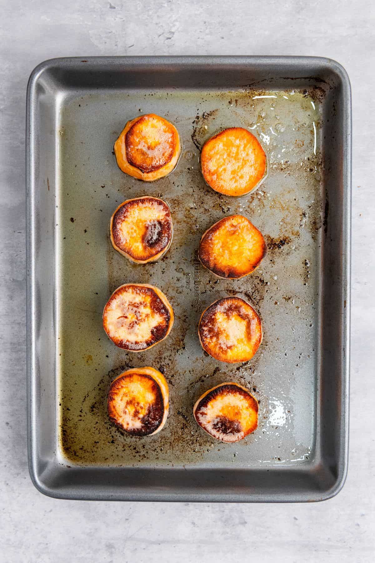Freshly baked sweet potato slices on a baking tray.