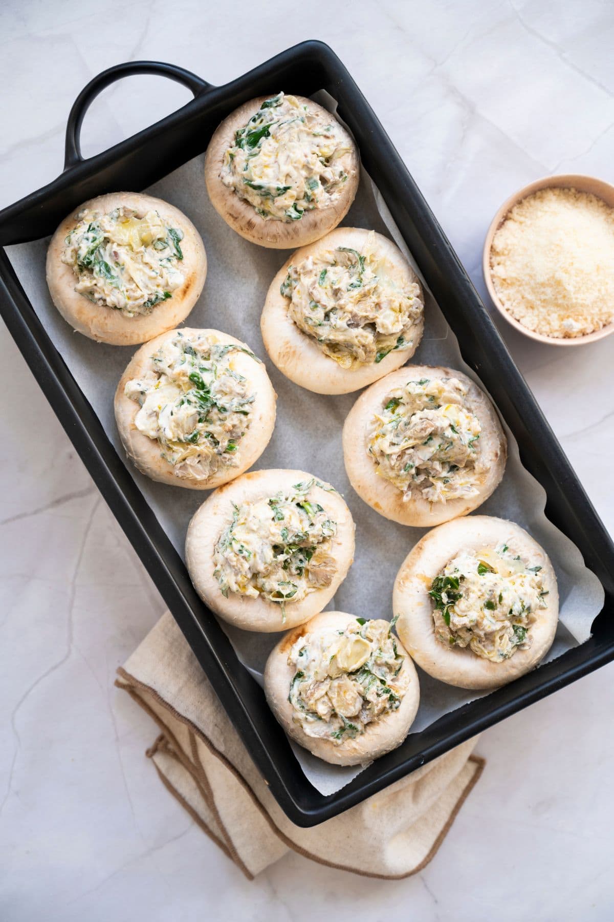 A serving dish with neatly arranged stuffed mushroom with cheese parmesan on the side.