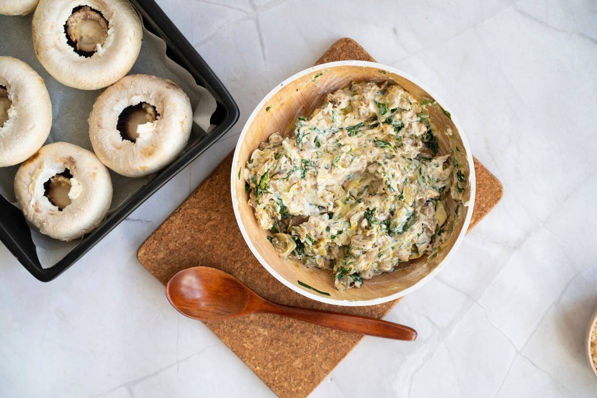 A creamy spinach, mushroom stem, and artichoke mixture resting in a medium pan after cooking.